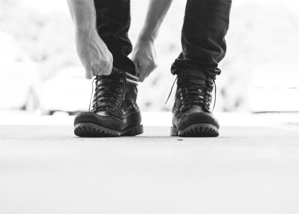 Black-and-white shot of hands lacing black leather boots