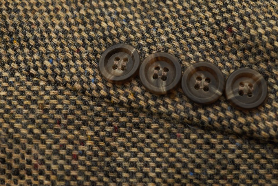 Macro of brown flecked tweed with four horn buttons on a cuff