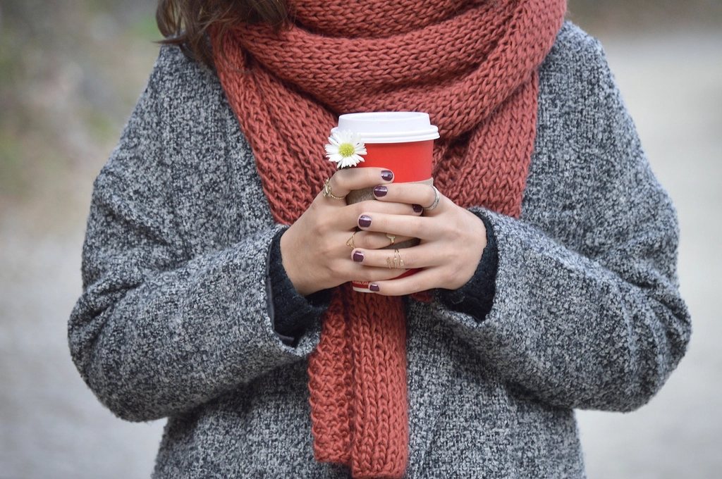 Grey wool coat and rust knit scarf, hands holding a takeaway cup, face out of frame