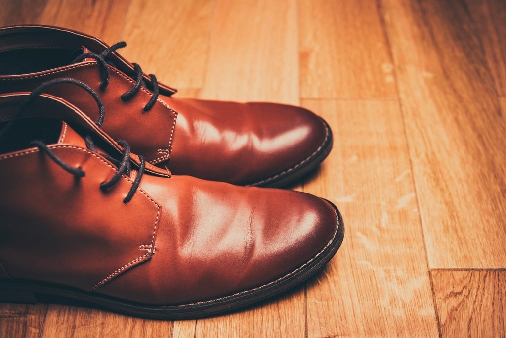 Polished brown leather chukka boots on a warm wooden floor