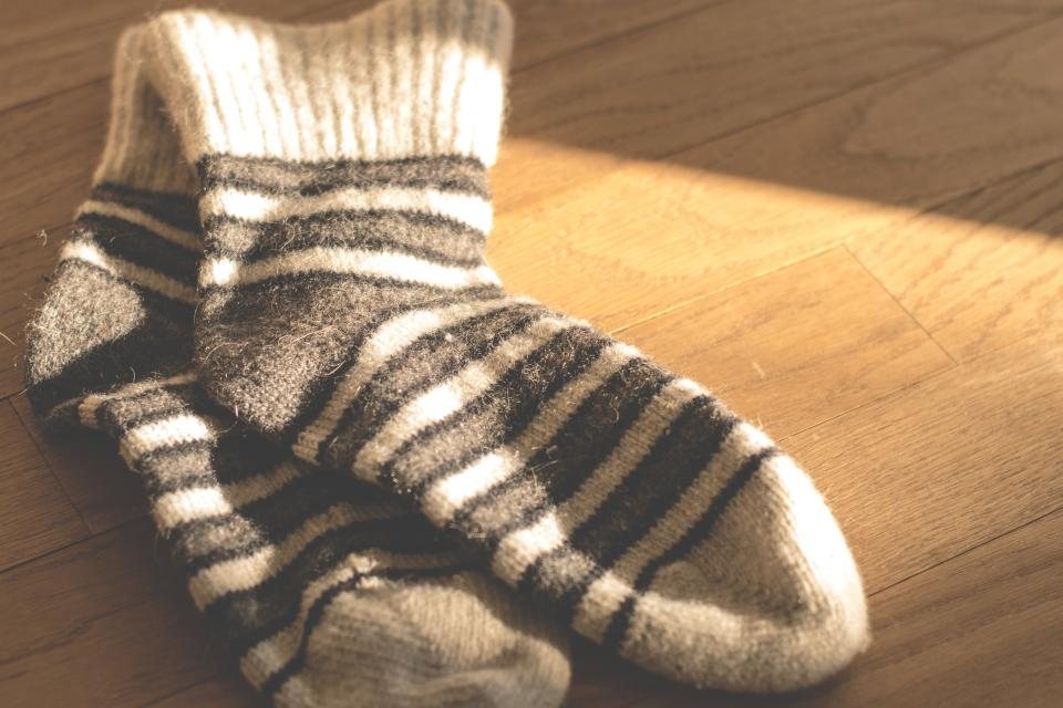 Pair of grey and cream striped wool socks on a sunlit wooden floor