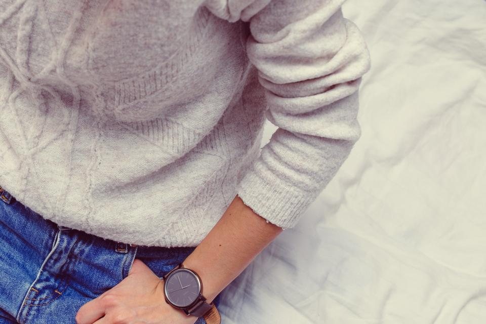 Cream cable-knit sweater worn with light-wash jeans and a dark watch
